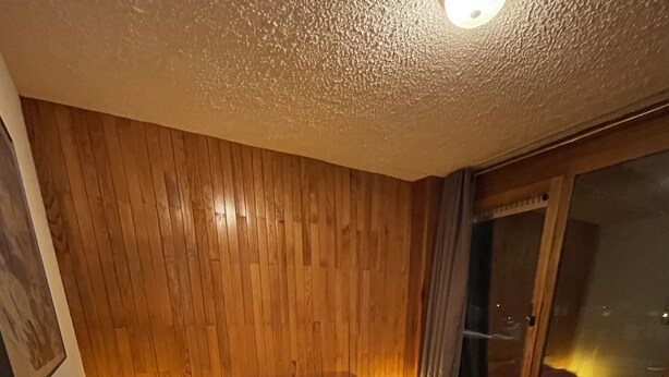 Ein Schlafzimmer mit einem hölzernen Kopfstück, einer rosa Tagesdecke und einem Nachttisch mit einer Lampe.