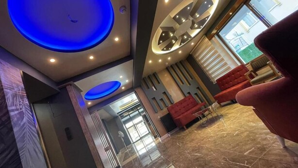A modern lobby with a marble floor, red seating, and a large circular light fixture on the ceiling. - Yalova Sezon Hotel (Yalova)