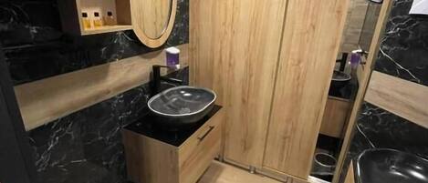 A compact kitchen with a black countertop, wooden cabinets, and a marble backsplash.