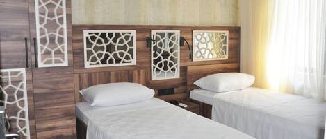 A hotel room with two single beds, wooden headboards, and decorative wall panels.
