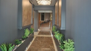 A modern hallway with a marble floor, wooden paneling, and a staircase leading to an upper level. - Yalova Sezon Hotel (Yalova)