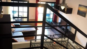 Una scala che conduce a una camera da letto con un letto e una scrivania.