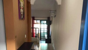 Un corridoio con pavimento piastrellato, una porta blu e una mensola a parete.