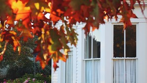 Une maison blanche avec une clôture en piquets et des parterres de fleurs.