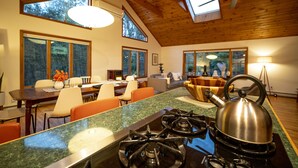 A modern kitchen with a gas stove, a kettle, and a dining area with a table and chairs.