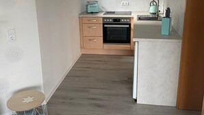 A compact kitchen with a built-in oven, a microwave, and a small island. - Vacation apartment Höhlenblick in Balve/Sauerland (Balve)