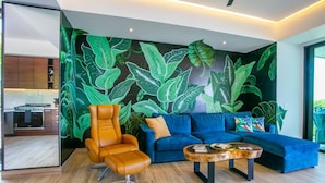A modern living room with a blue sofa, an orange chair, and a coffee table. - Ocean-view terrace, Pool & BBQ, Conchas Chinas (Puerto Vallarta)