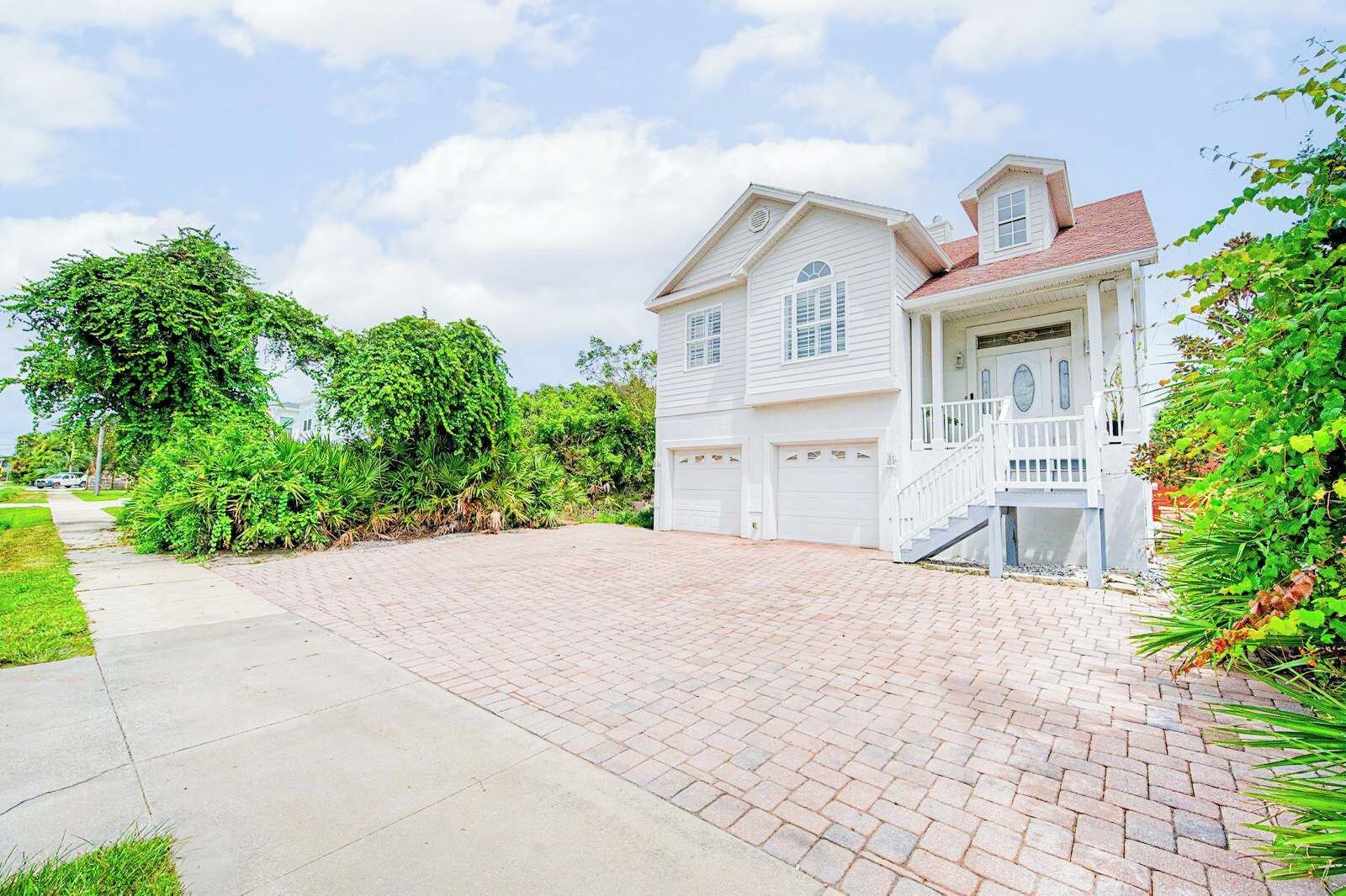 A two-story house with a garage, a driveway, and a well-maintained garden.
