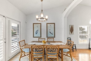 A dining area with a wooden table and chairs, a chandelier, and artwork on the walls.