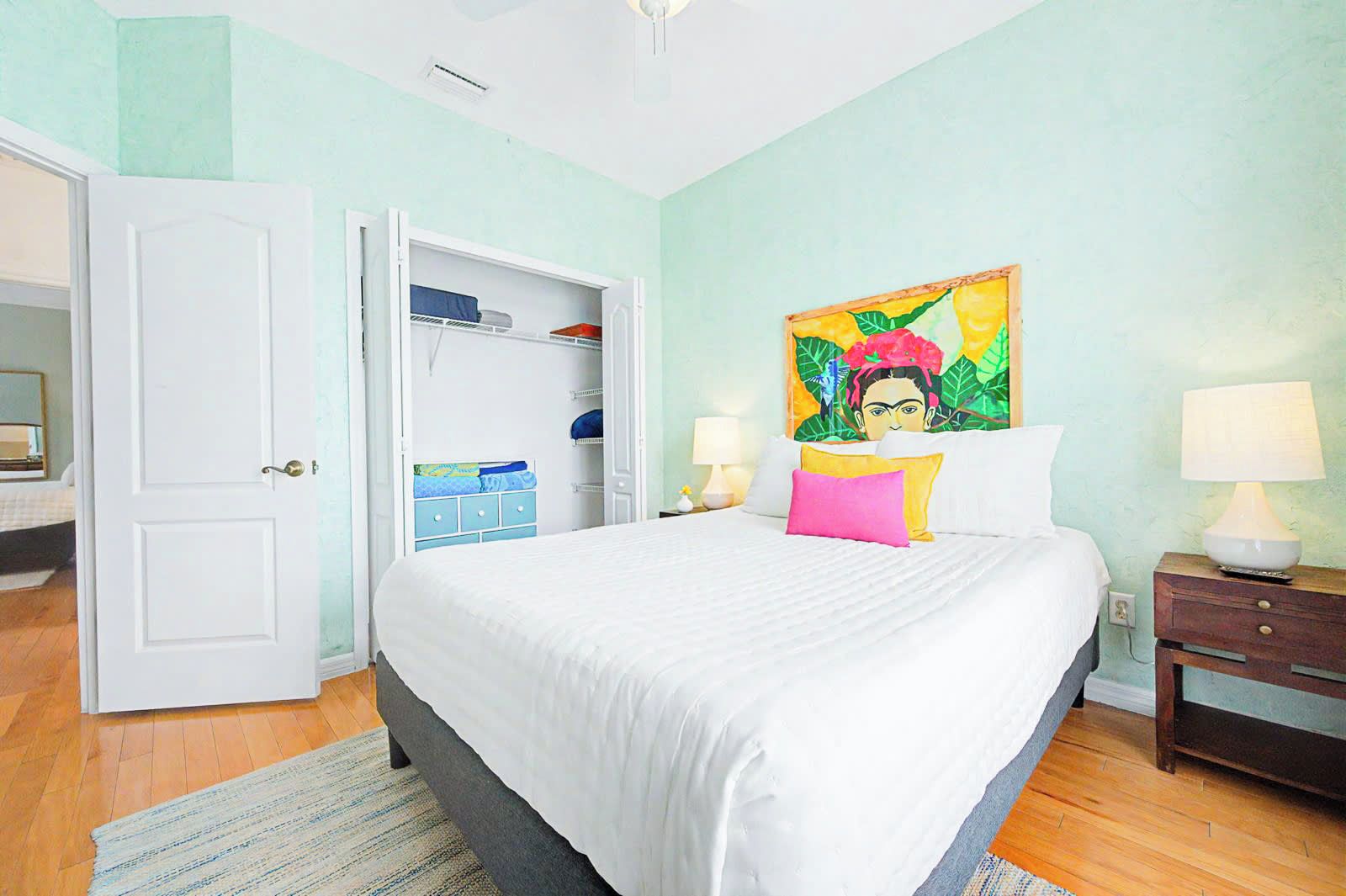 Une chambre à coucher avec un lit, des lampes de chevet, une armoire et un tableau au mur.