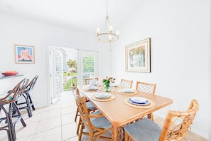 A dining area with a wooden table set for six, surrounded by wicker chairs.