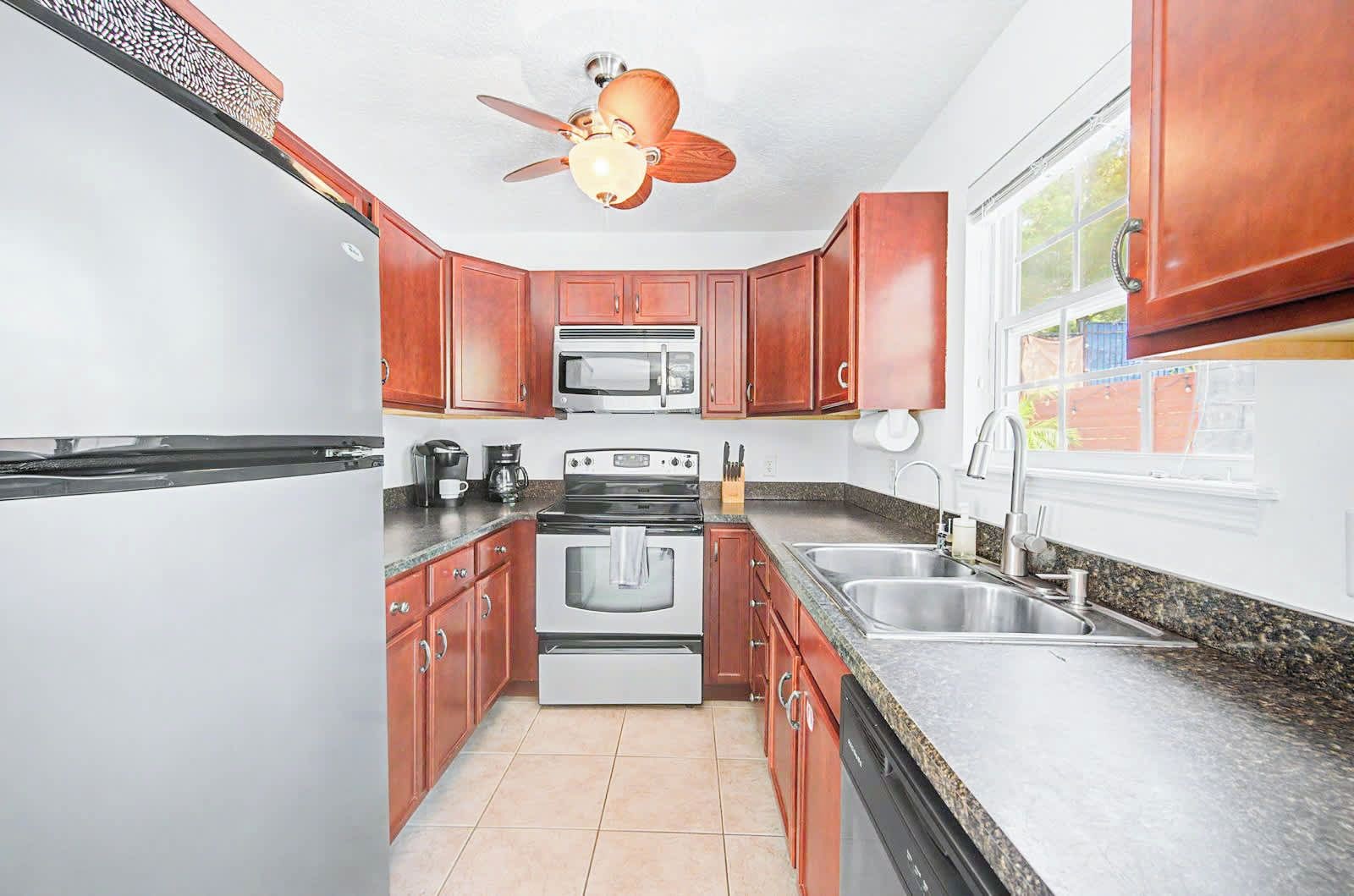 A kitchen with wooden cabinets, a microwave, a stove, and a sink.