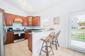 A kitchen with wooden cabinets, a stainless steel stove, and a large island with bar stools.