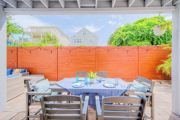 An outdoor patio with a table set for four, surrounded by wooden chairs.