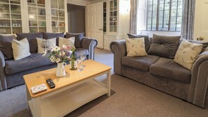 A living room with two grey sofas, a wooden coffee table, and a bookshelf. - Garden View (Wellington)