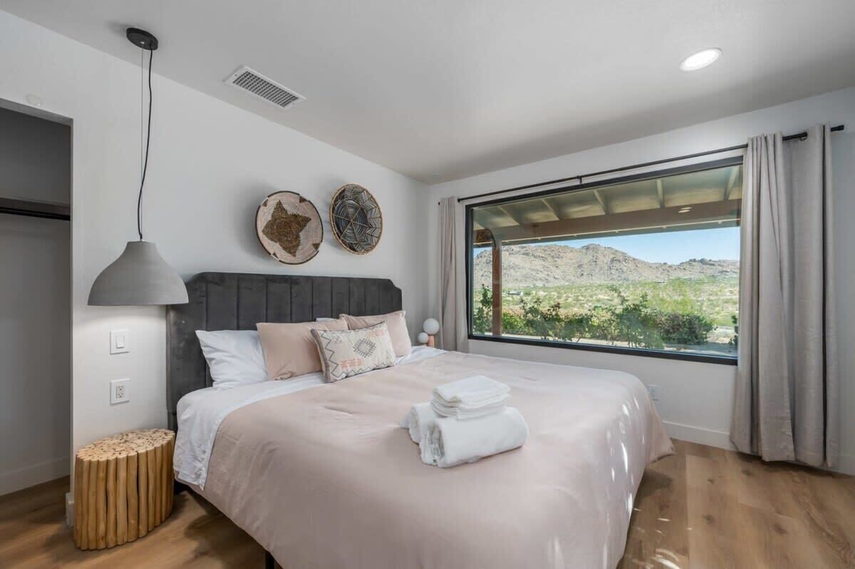 A bedroom with a large bed, a view of the desert, and a modern design.