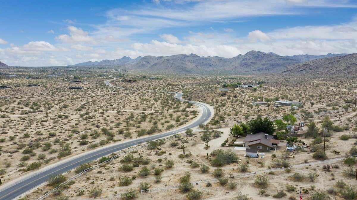 A desert landscape with a winding road, sparse vegetation, and distant mountains.