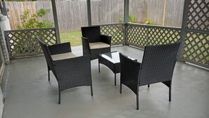 A covered patio with a table and four chairs.