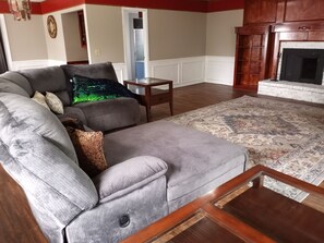 Een woonkamer met een grijze bank, een klein houten tafeltje en een vloerkleed met dessin.