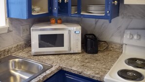 A kitchen with blue cabinets, a white microwave, a toaster, and a stove.