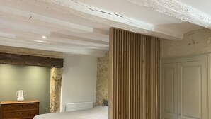 Een slaapkamer met een bed, een houten dressoir en een kledingkast.