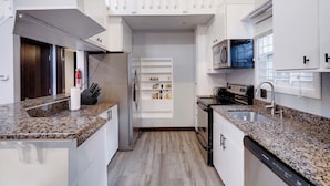 A modern kitchen with white cabinetry, granite countertops, a built-in microwave, and a stainless steel sink. - Luxury Mountain Home 5BD/3BA, AC, 3 Min to Pool, Near Major Pocono Attractions. (Tobyhanna)