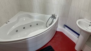 A bathroom with a white bathtub, a sink, and a red floor. - Peaky Blinder themed hotel rooms/studio apartments (Dudley)