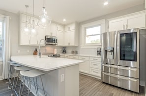 Enjoy cooking in this well-equipped kitchen with a large island, bar stools, and stainless steel appliances.