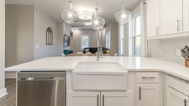 A modern kitchen with a large island, stainless steel appliances, and pendant lighting.
