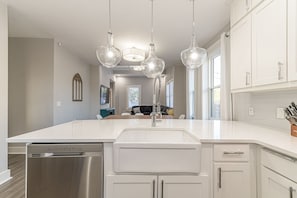 Cocina moderna con una isla grande, electrodomésticos de acero inoxidable e iluminación colgante.
