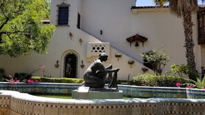A courtyard with a tiled fountain, a statue, and a building with a tiled facade and a bell.