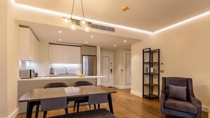 Eine moderne Küche mit weißen Schränken, einem Edelstahlkühlschrank und einem Essbereich mit Holztisch und Stühlen.