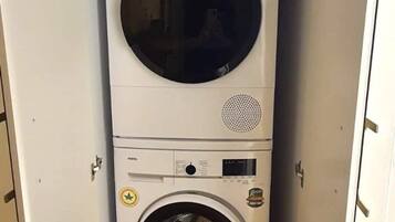 Et lille vaskerum med en vaskemaskine med lodret åbning og en tørretumbler med foroven.