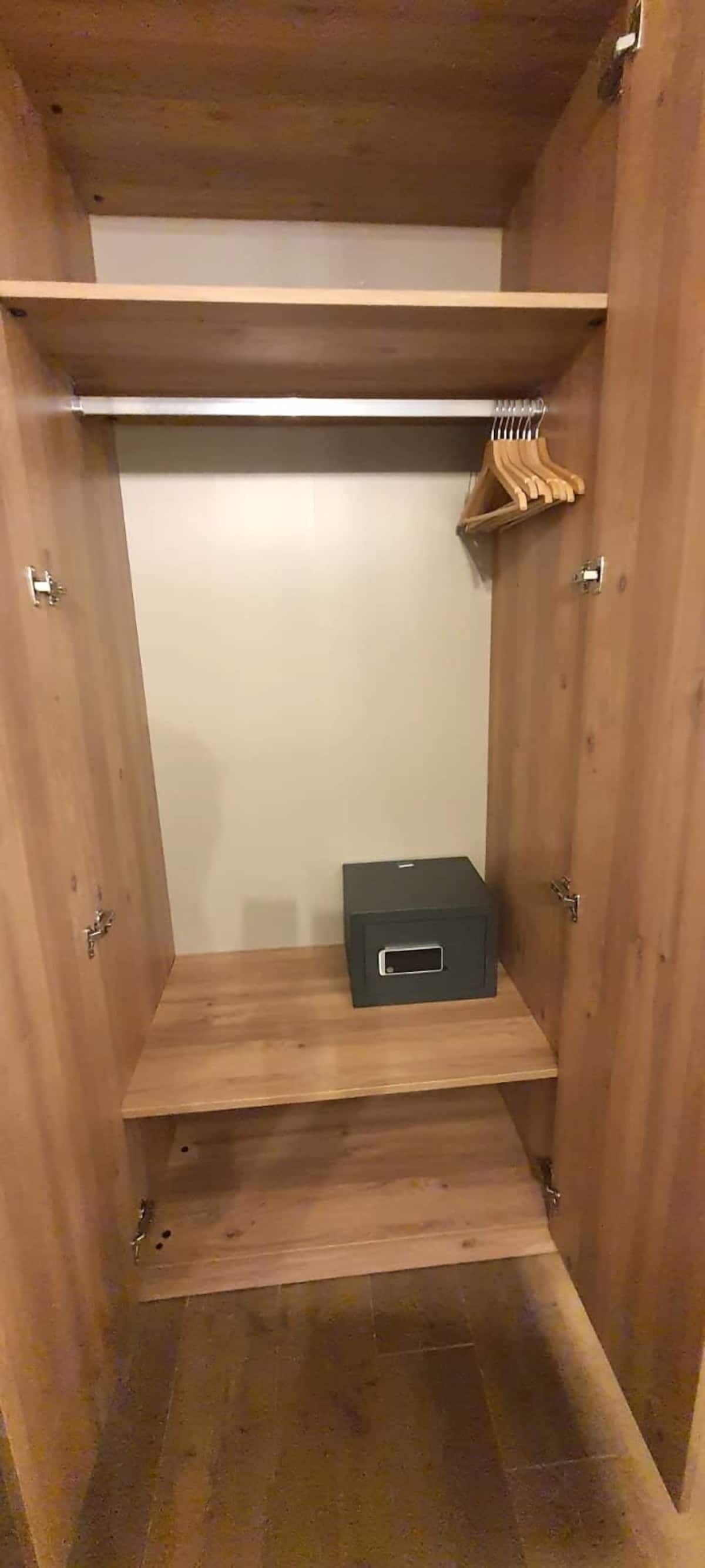 Une armoire en bois avec deux étagères et une tringle pour suspendre les vêtements.