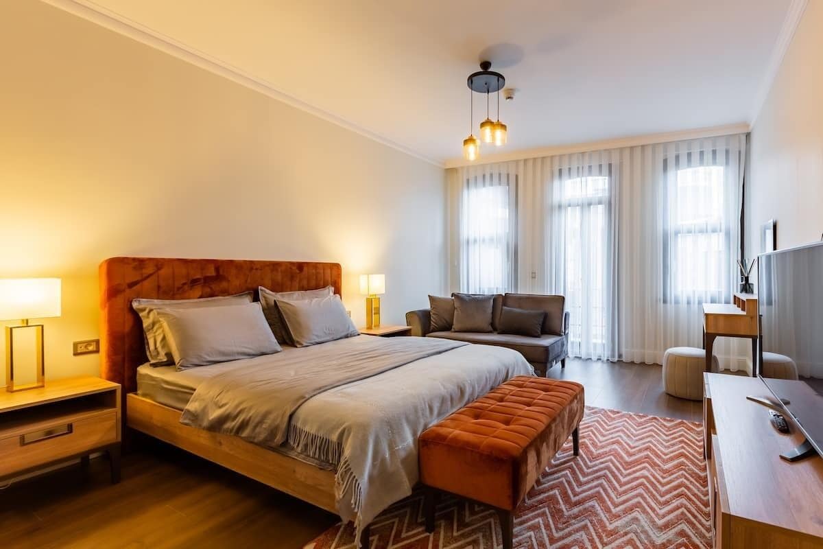 A modern hotel room with a large bed, a desk, a chair, and a TV.