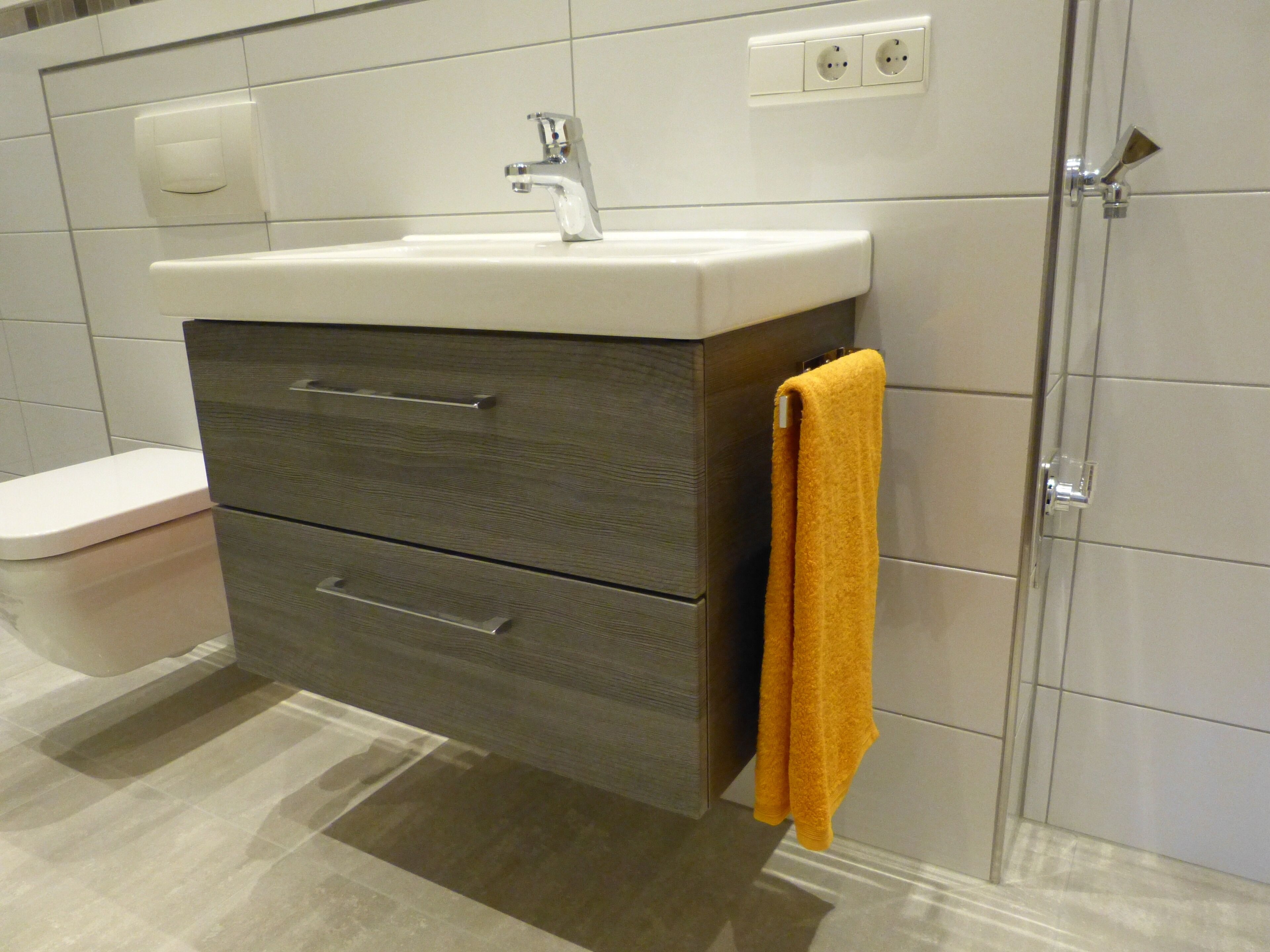 A bathroom with a white sink, a toilet, and a towel hanging on a rack.