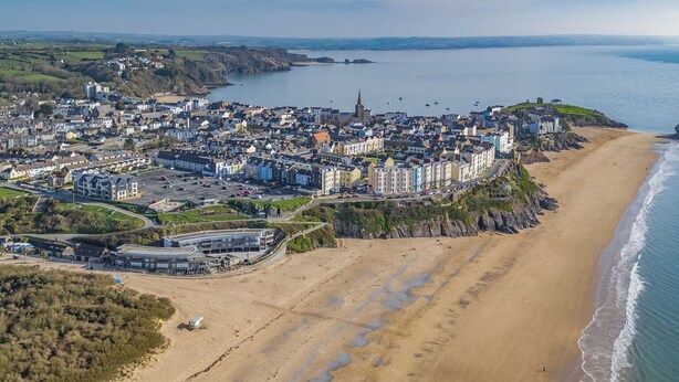 An aerial view of a coastal town with a beach, buildings, and a church. - Arcadia House - Close to Beaches, Harbour and Town (Tenby)