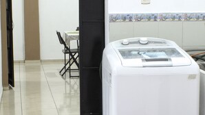 Una cocina con un refrigerador blanco, una puerta negra y un salpicadero de azulejos.