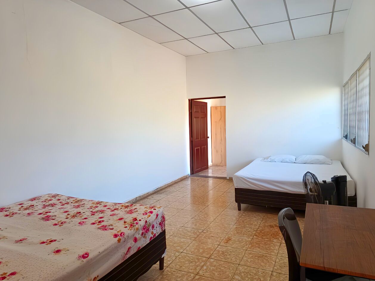 Una habitación con dos camas individuales, una mesa de madera y una silla.