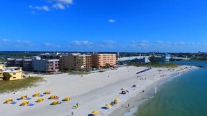 A beach with umbrellas and buildings in the background.
