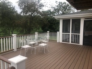 A covered outdoor deck with a glass enclosure, white railings, and a table with chairs. - Nonquit Cottage by Sakonnet Farm & Stays (Tiverton)