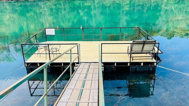 A floating dock with two platforms, each with a table and chairs, surrounded by calm turquoise water. - Riverfront House near Cow Shoals - King bed & WiFi (Heber Springs)