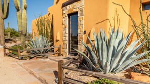 A building with a stone entrance, surrounded by cacti and agave plants. - Private Desert Oasis with Pool & Hot Tub, Game Room | Family & Pet Friendly (Scottsdale)