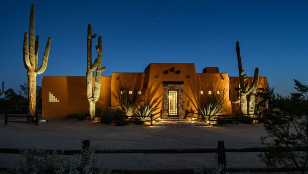 A desert-style building with a stone entrance, surrounded by cacti and a wooden fence. - Private Desert Oasis with Pool & Hot Tub, Game Room | Family & Pet Friendly (Scottsdale)