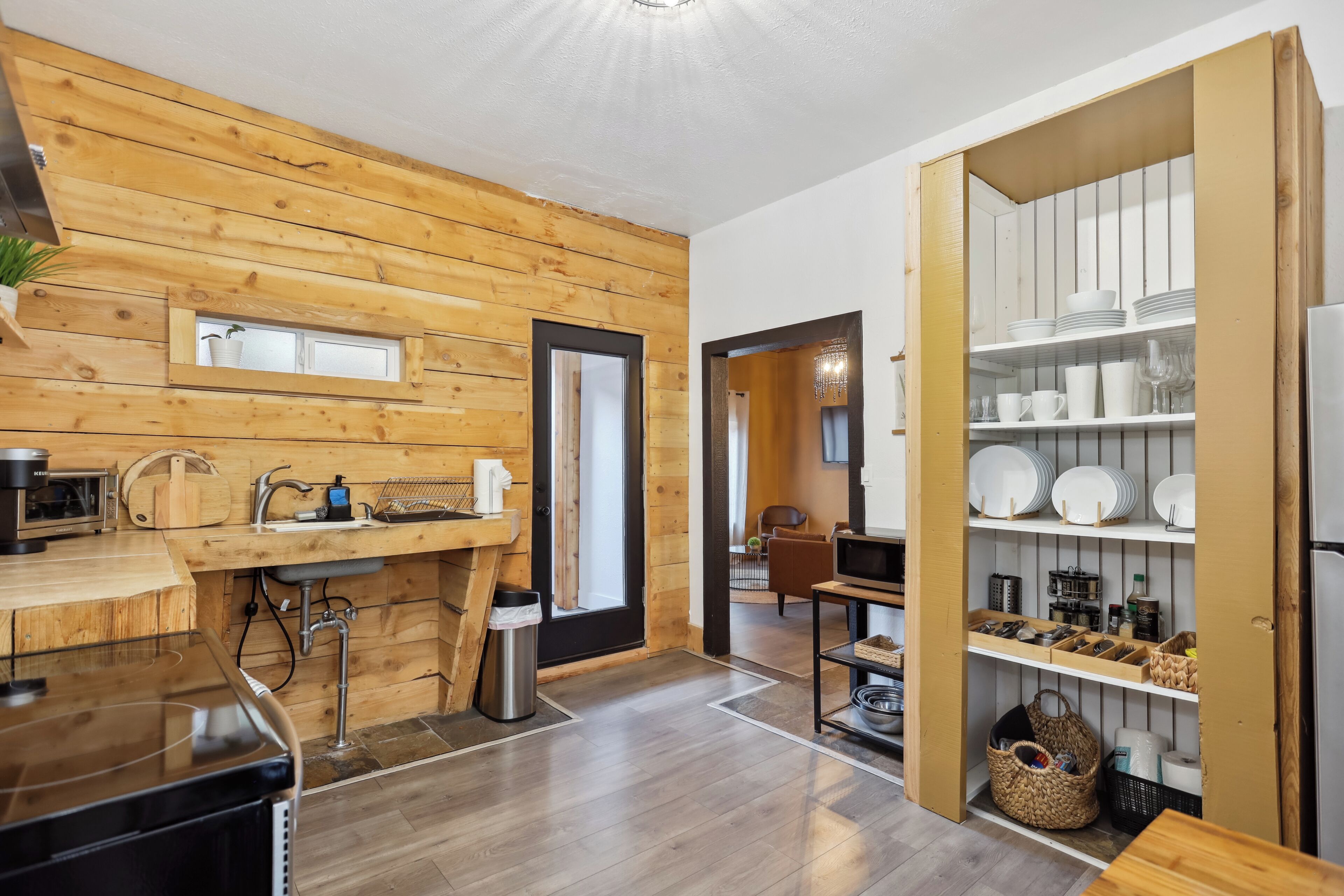 A modern kitchen with wooden paneling, a built-in sink, and a dining area with a wooden table and chairs.