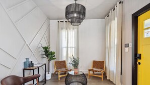 Ein modernes Zimmer mit einem runden schwarzen Tisch, zwei Holzstühlen, einem braunen Ledersessel, einer Topfpflanze und einer gelben Tür.