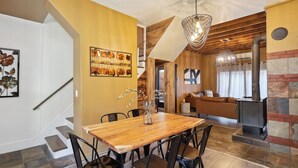 Ein Essbereich mit Holztisch, Stühlen, einer Chandelüster und einem Kamin.