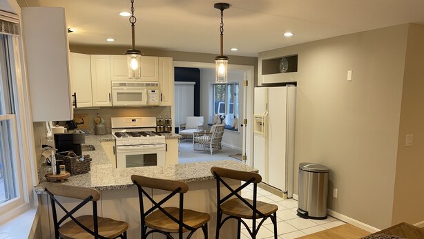 Una cocina moderna con una isla central, taburetes de bar y una mesa de comedor.