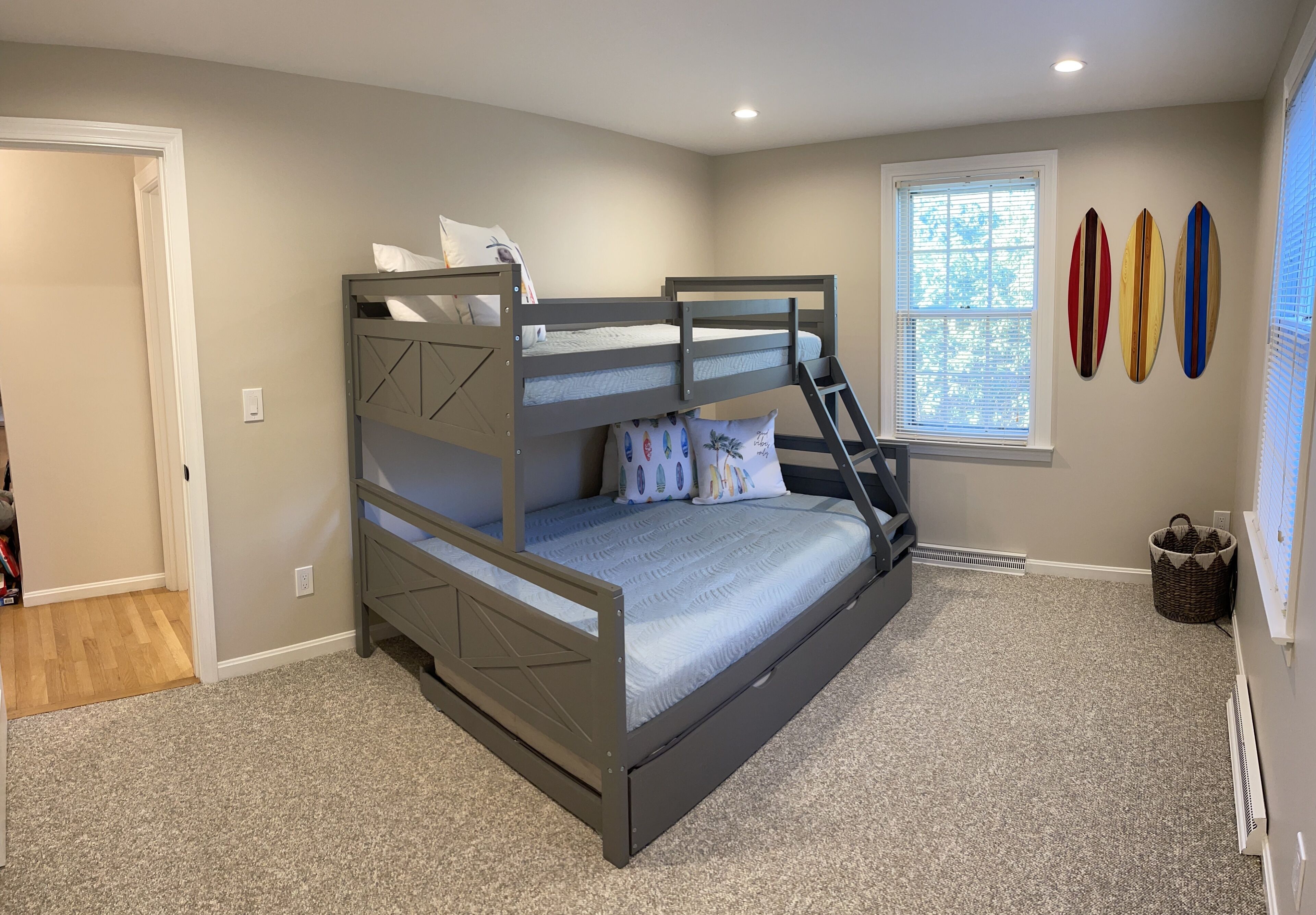 A bunk bed room with a window, a radiator, and a wall-mounted surfboard decoration.