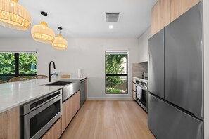 A modern kitchen with stainless steel appliances, wooden cabinets, and a large window.